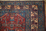 The corner of a vintage Malayer rug featuring a sapphire blue vine border and geometric motifs.