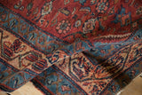 A close-up of a vintage Malayer rug folded to reveal its fine wool pile and detailed floral motifs.