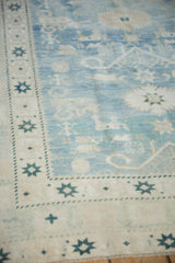 Distressed Oushak rug detail: faded powder blue field, sand border with teal starburst motifs.
