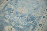 Close-up of distressed vintage Oushak rug showing powder blue field, abrashes, geometric blossoms.