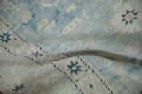 Distressed Oushak rug pile texture with dusty teal starbursts and sand abrashes.