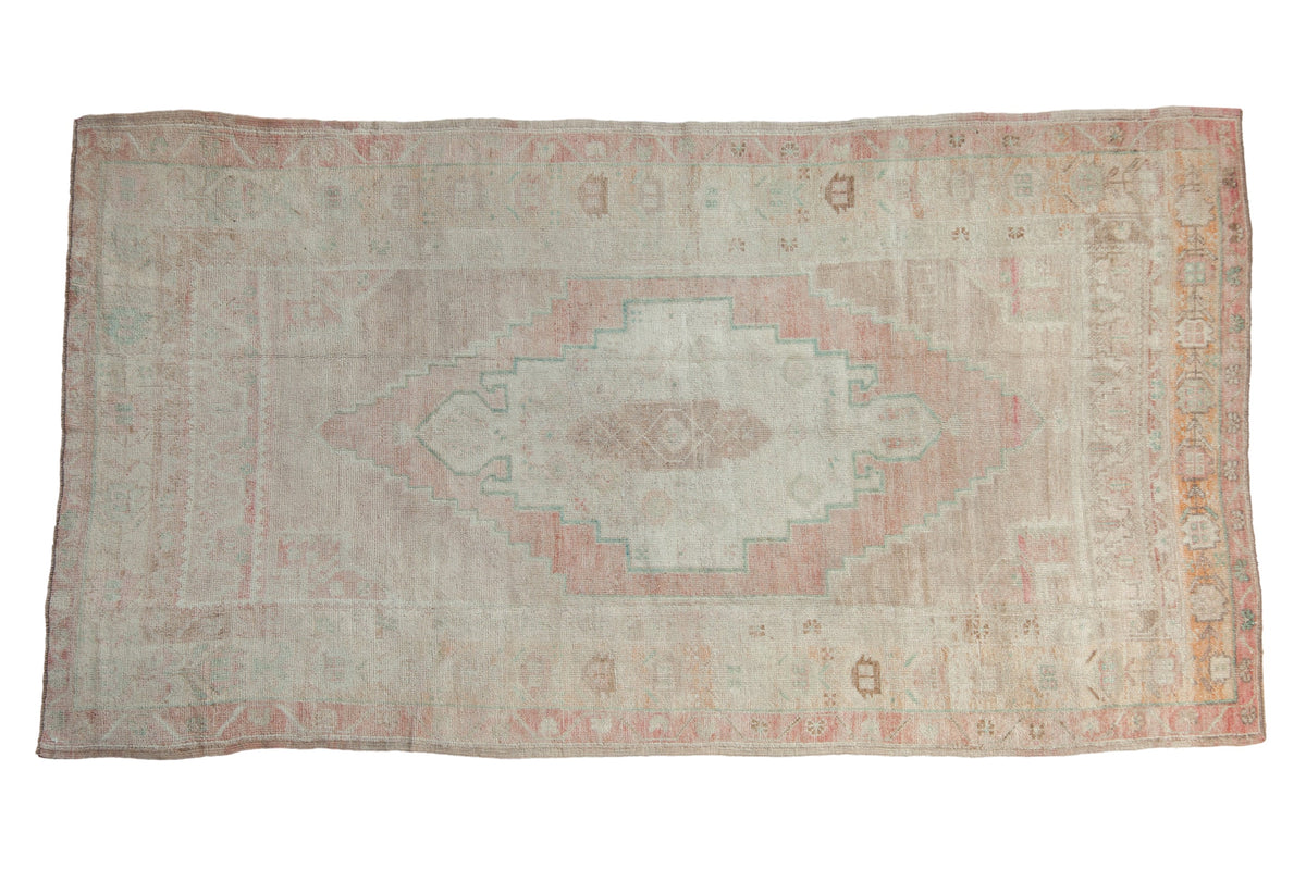 Vintage distressed Oushak rug with a central stepped medallion in soft blush, ivory, and pale ocean green.