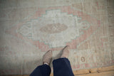 Distressed texture on the stepped geometric medallion of a vintage Turkish Oushak rug in blush and ivory.