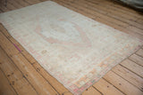 A vintage Turkish Oushak rug viewed from a high angle, showcasing its lustrous sheen and distressed pile.