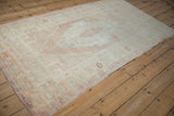 Distressed Turkish Oushak rug showing high sheen across its soft blush and ivory medallion.