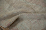 Textured low pile and visible knot heads on a softly draped vintage Oushak rug.