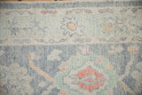 Textured pile of a distressed Oushak rug showing nuanced palmettes with faded blues and peach accents.