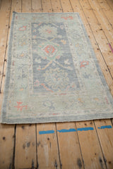 Close-up of distressed Oushak rug's softened texture, pale blue palmettes, and terra cotta accents.