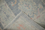 Distressed Oushak rug pile with varied blue tones, exposed foundation, and intact selvedge.