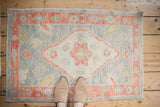 Decorative distressed Oushak rug with soft, muted tones viewed from above.