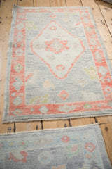 Small distressed Oushak rugs with diamond medallions shown together from an angled view.