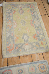 Close-up of distressed Oushak rug corner, tropical palmettes in lime green and pale tangerine.