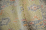 Close-up of distressed Oushak rug's softened pile, with muted lime green and blush palmettes.