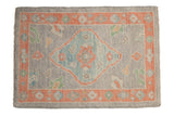 Distressed Oushak rug mat with faded peach border, blue diamond medallion, and oxidized silver field.