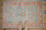 Close-up of hand-knotted Oushak rug: powder blue diamond medallion, soft coral border, patina texture.