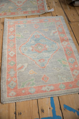 Distressed Oushak mat with light blue diamond medallion and coral floral border.