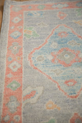 Distressed Oushak rug with softened peach floral border and powder blue medallion section.