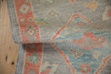 Distressed Oushak rug's softened pile texture featuring oxidized silver, coral, and blue hues.