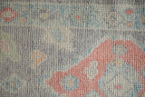 Textured pile of the distressed Oushak rug, showing faded oxidized silver and pale ruby floral elements.