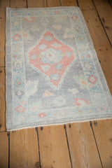 Patina on distressed Oushak rug, showing pale ruby red diamond medallion with powder blue details.