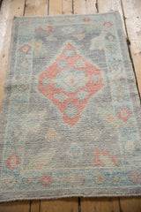Softened hand-knotted pile of distressed Oushak rug; ruby, blue, sand diamond medallion.