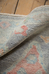 Softened pile texture with pale pink, blue floral motifs on a distressed Oushak rug.