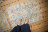 Distressed Oushak rug mat shown underfoot for scale, featuring a blue and silver floral medallion.