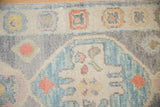 Close-up of the Oushak rug's stylized pomegranate border with soft silver and blue wool pile.