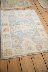 Angled view of a distressed Oushak rug's soft pile, silver ground, and pastel medallion.