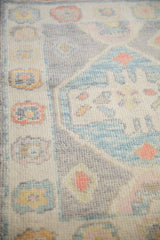Even hand-knotted wool pile showing stylized motifs in silver, powder blue, and rose.