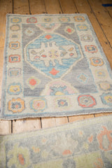 Full perspective of the distressed Oushak rug mat, showing its silver field, blue medallion, and floral border.