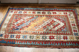 Vibrant diagonal stripes and geometric star borders of the antique Kazak rug.