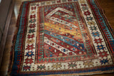 Vibrant geometric border motifs and diagonal stripes on an antique Kazak rug.