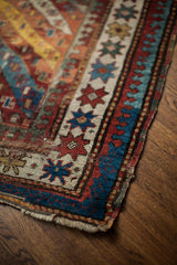 Textured edge of the antique Kazak rug, showing colorful geometric motifs and light wear.