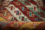Articulated pile of an antique Kazak rug with vibrant red, blue, and cream geometric motifs.