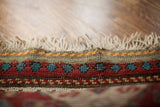 Hand-knotted fringe and colorful geometric border pattern of an antique Kazak rug.