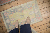 Distressed Oushak rug displaying softened lime green pile and blush palmette patterns.