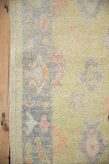 Distressed Oushak rug detail: intact side selvage and soft lime, grey, blush palmette pile.