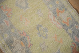 Distressed Oushak rug's soft pile, featuring nuanced lime green and pale tangerine palmettes.