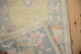 Distressed Oushak rug corner detail, showing soft pile, woven reverse, and pastel palmettes.