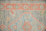 Close-up of the textured wool pile on a distressed Oushak rug showing its floral border.