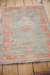 Distressed Oushak rug mat from an angle, showing its even pile in silver, blue, and coral.