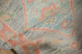 Soft texture of a distressed Oushak rug's hand-knotted pile in silver, blue, and tangerine.