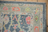 Close-up of distressed Oushak runner's border, with floral palmettes in celadon green and cantaloupe.