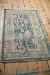 Distressed Oushak rug detail: pastel floral palmettes on blue field, vibrant pomegranate border.