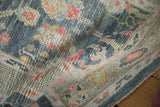 Distressed Oushak rug's folded pile, featuring colorful palmettes, vines, and softened patina.