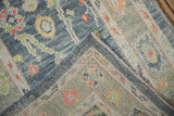 Distressed Oushak rug corner revealing intricate floral motifs, softened patina, and intact selvage.