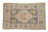 Distressed Oushak rug with a diamond medallion in dusty blue and ivory with saffron and orange accents.