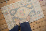 A person standing on a distressed Oushak rug shows its scale and soft floral pattern.