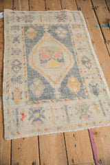 Perspective view of a distressed Oushak rug with a diamond medallion on a dusty blue field.